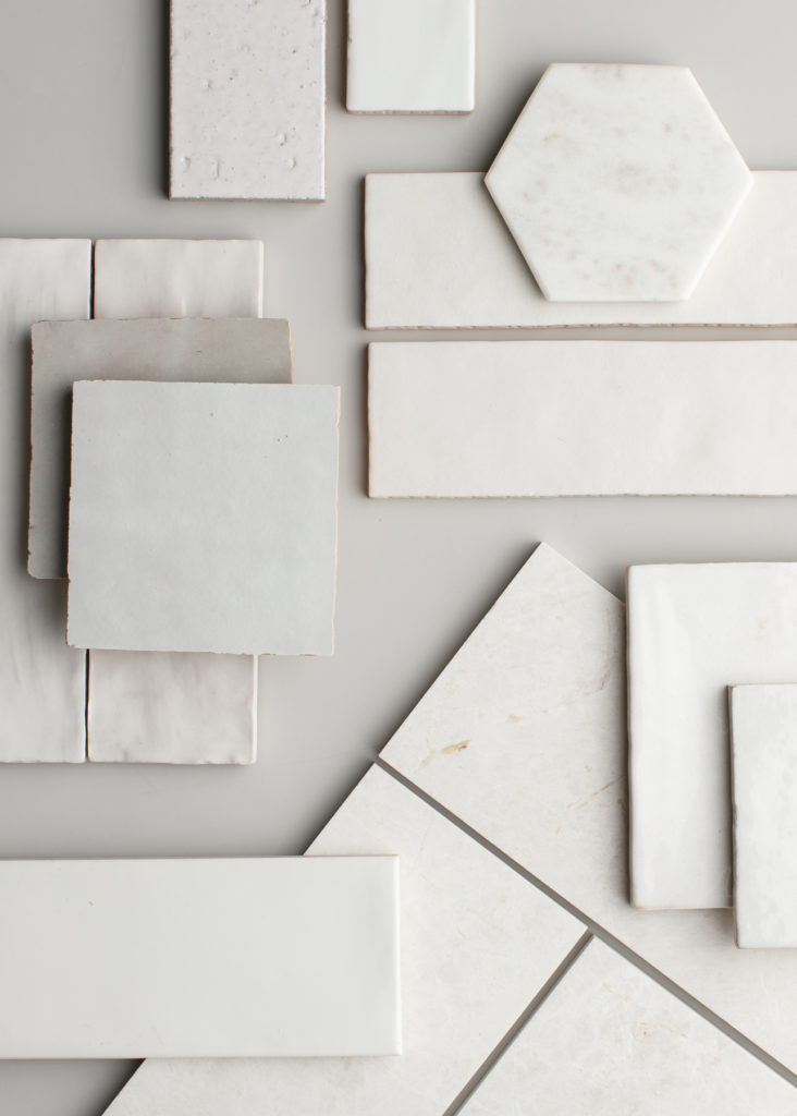 A close up of various white and grey tiles scattered on a grey counter.