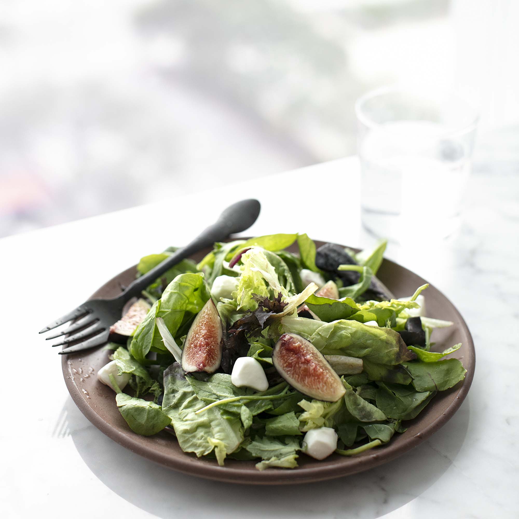 A salad with figs and a fork.